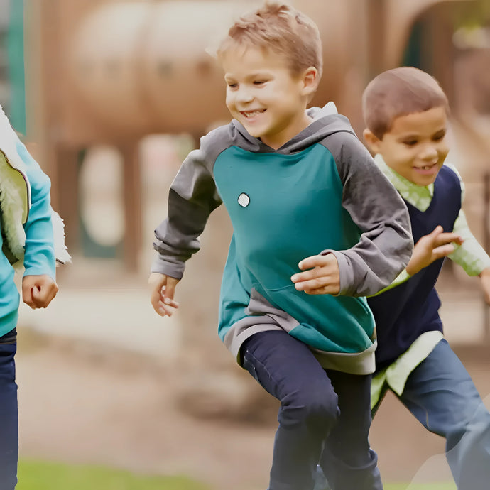 Two young boys running outside on a playground